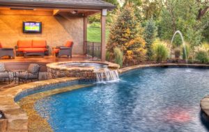 An Entertainer's Delight in Parkville pool and spa with waterfall and fountains with outdoor living space by Backyard by Design KC