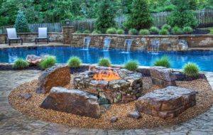 A firepit in front of a pool with waterfalls