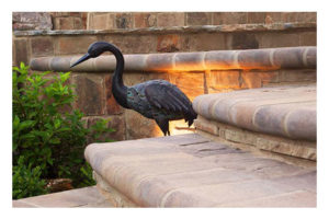 Image of iron heron by stonework steps
