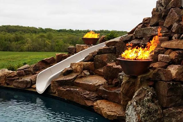 A slide leading into a pool with fire features