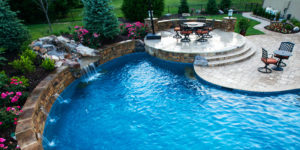 A custom backyard pool with waterfall and patio