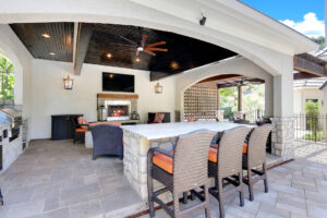 Backyard by design patio enclosure with bar, fireplace, and furniture